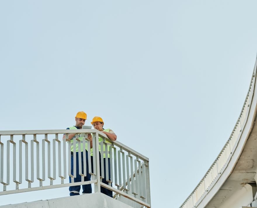Two engineers wearing hard hats inspecting an elevated structure