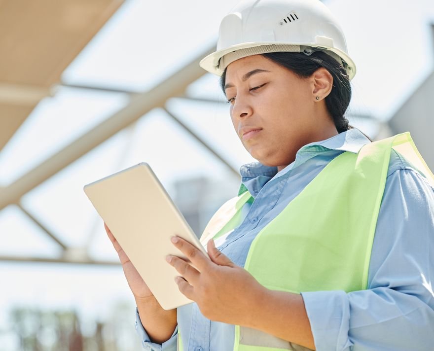 Engineer in a hard hat using a tablet at an outdoor construction site