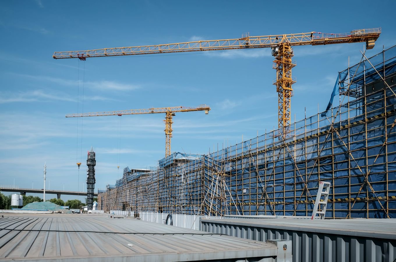 Construction site with tower cranes and scaffolding under a clear sky