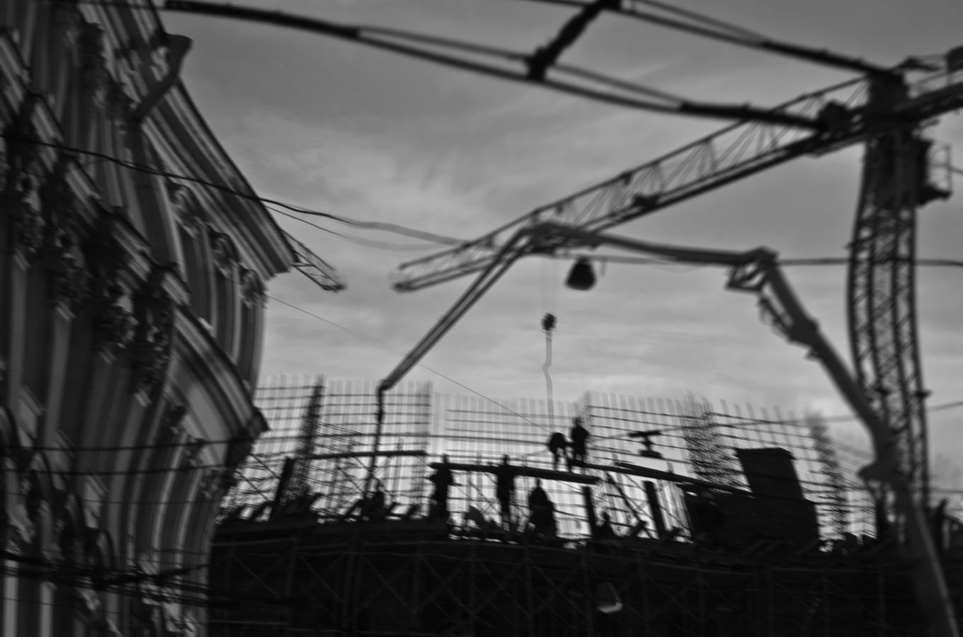 Silhouettes of builders on a construction site with cranes