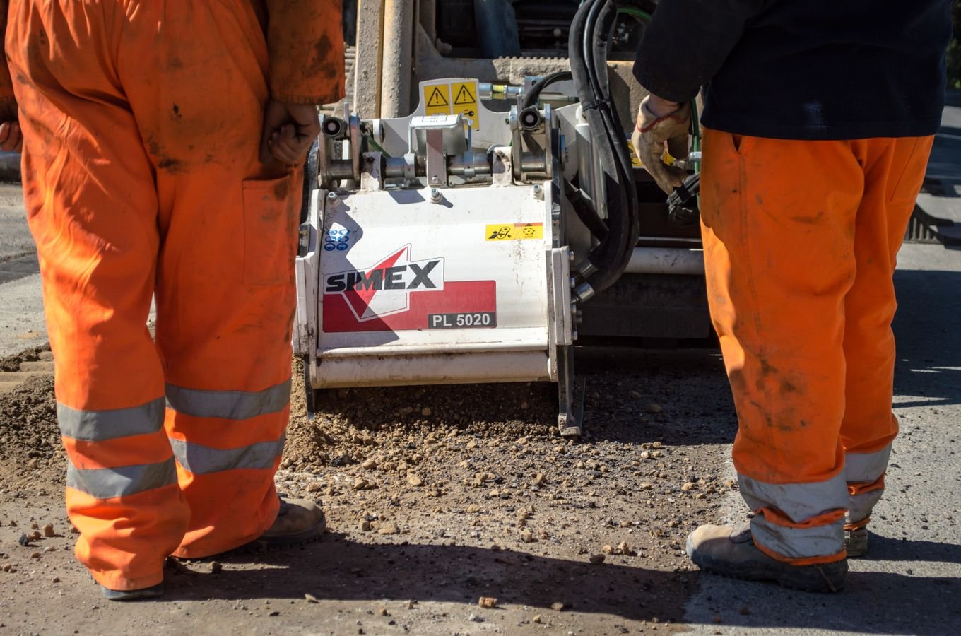 Workers operating an asphalt paving machine during road maintenance
